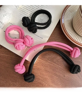 Détail de chouchous tissés très élastiques noir et rose sur un bureau en bois