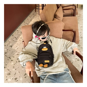 Bambino con borsa a tracolla a forma di papera nera in nylon con dettagli 3D in un cafe