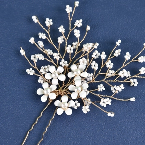 Detail of white flower and bead bridal hair pin with golden wire on blue background