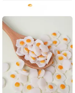 Macro shot of miniature PVC fried egg charms displayed on a wooden spoon