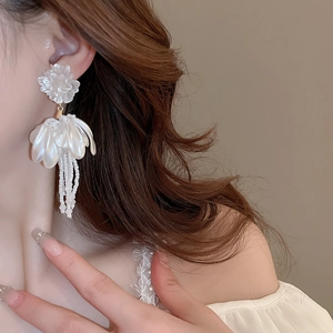 Detail of white flower tassel earrings with pearls on model for an elegant look