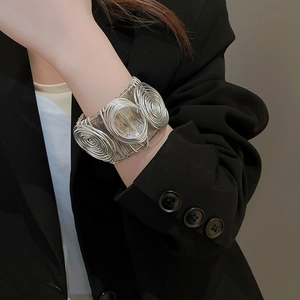 Detail of silver spiral wrap wide cuff bracelet styled with a black blazer outfit