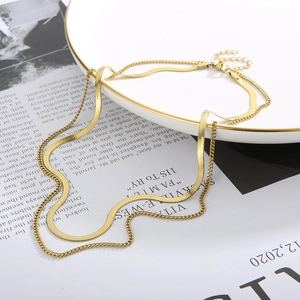Detail of layered gold snake bone chain necklace on a ceramic plate for women