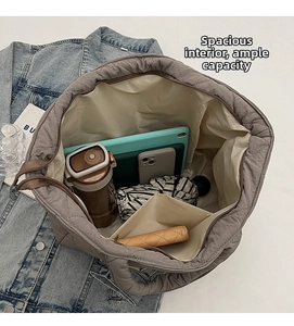 Detailed interior of a grey quilted tote bag showing large storage capacity and inner pocket