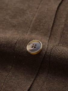 Detailed close-up of a brown knit cardigan with a tortoiseshell resin button and ribbed texture