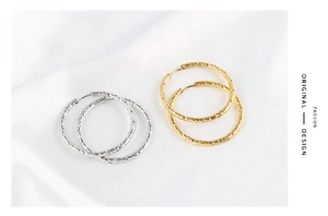 Detail of vintage textured gold and silver hoop earrings on white silk fabric