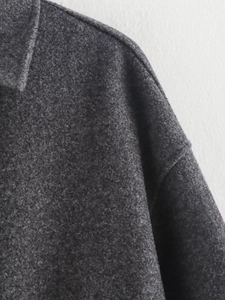 Detailed close-up showing the grey wool blend fabric texture and shoulder seam of the coat