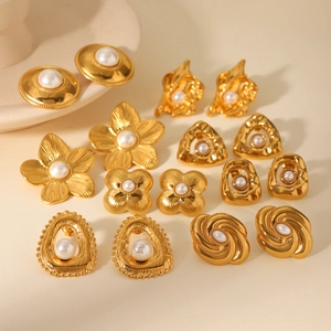 Flat lay of vintage gold stainless steel earrings with white pearls in floral and geometric shapes