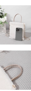 Detail of white plush tote bag with light brown handle and golden metal chain link