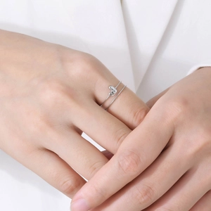 Gros plan d'une bague coeur en argent sertie de zircons portée au doigt