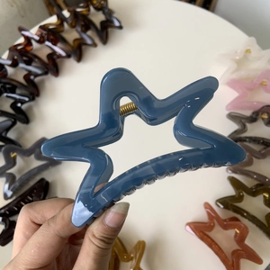 Detail of star-shaped Morandi blue hair claw clip with golden metal spring and glossy finish
