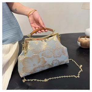 Detail of light blue satin evening bag with gold floral embroidery and amber resin handle