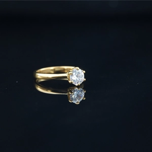Classic gold titanium ring with a brilliant round cut moissanite on a black reflective surface