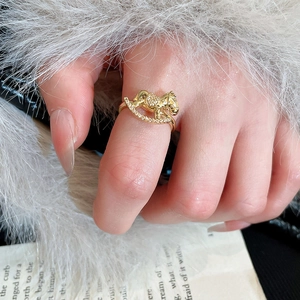 Close-up of golden rocking horse ring with zircon stones on a soft fabric background