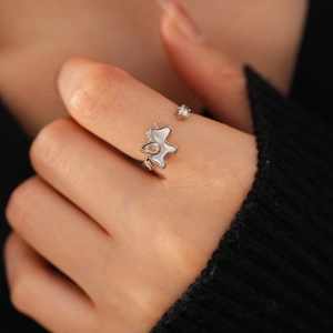 Detailed close-up of a silver ring with shell and zircon on a model's hand