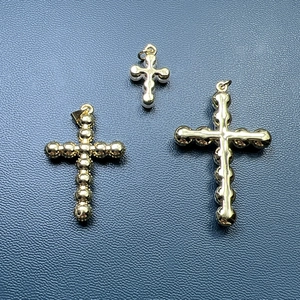 Golden metal pearl cross pendant set for jewelry making on dark textured surface