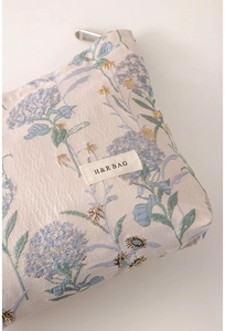 Close-up of portable cosmetic bag with blue floral embroidery and metallic zipper detail