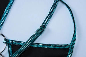 Dettaglio ravvicinato delle spalline glitterate blu e anelli metallici sul vestito