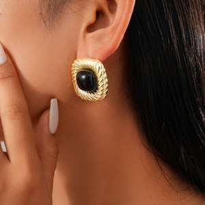 Detailed close-up of a vintage golden twisted metal earring with a large black oval gemstone