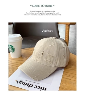 Detail of apricot distressed cotton baseball cap with ripped fabric on a cafe table