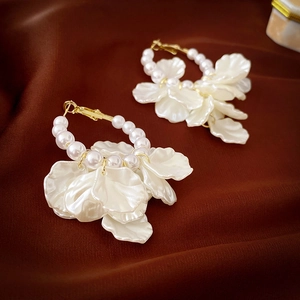 Detail of elegant pearl petal hoop earrings on luxury satin background