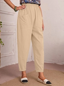 Detail of beige cotton linen pants featuring an elastic waist and large front pockets