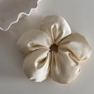 Detail shot of a large beige floral scrunchie in premium glossy satin fabric