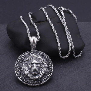 Macro shot of retro stainless steel lion head pendant on black pebbles with rope chain
