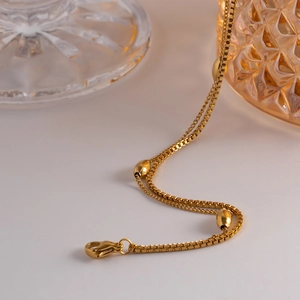 Close-up of golden double-strand bracelet with oval beads and secure lobster clasp
