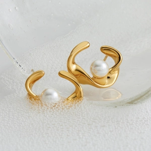 Elegant gold twisted C-shape earrings with central white pearls on a textured background