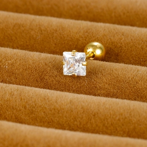Close-up of golden square zircon stud earring with threaded ball back on velvet