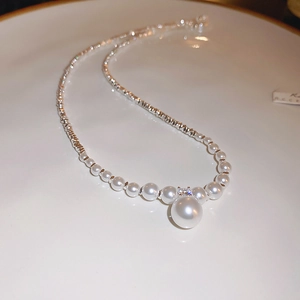 Detail of zircon pearl pendant necklace on a ceramic plate with silver metal chain