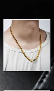 Detailed close-up of golden Cuban chain with green rectangular malachite pendant on model