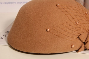 Detailed close-up of brown wool beret featuring elegant mesh veil and pearl bead accents