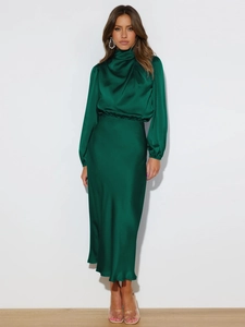 Detailed view of the dark green satin dress fabric with a silky high-gloss texture