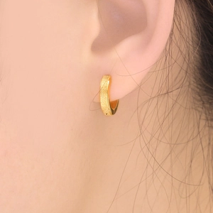 Macro shot of matte gold stainless steel hoop earrings with sandblasted finish texture