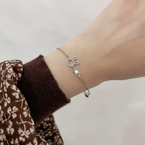 Close-up of silver hollow rabbit and carrot charms on a delicate metal chain bracelet