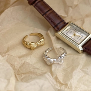 Detail of bow-shaped 925 silver rings in gold and silver finish with S925 hallmark