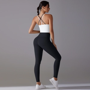 Détail du soutien-gorge de sport blanc à dos croisé et du legging de yoga noir taille haute