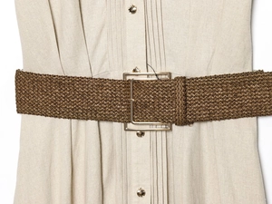 Detail of beige linen dress texture with brown braided belt and metallic buckle