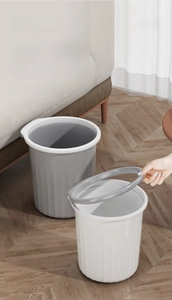 Detail of grey and white plastic waste bins with press ring on wooden floor