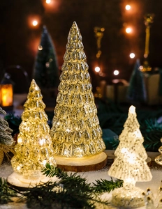 Detail view of glowing glass Christmas tree lamp with warm LED lights on snowy base