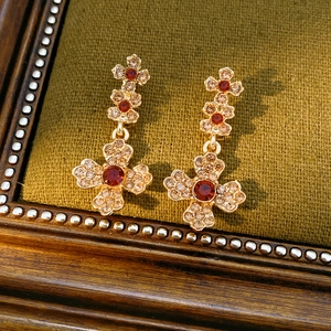 Detail of vintage gold clover earrings with red and champagne crystals on green velvet
