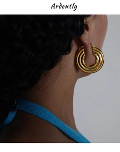 Close-up of elegant triple hoop earrings in polished gold finish worn by a female model