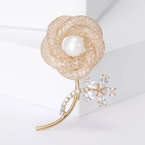 Elegant gold hollow rose brooch with large pearl and sparkling crystals on white block