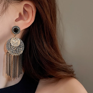 Close-up of bohemian tassel earrings with vintage portrait coin and crystal studs