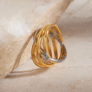 Macro detail of intertwined multi-layer gold and silver 18K steel snake ring on raw stone