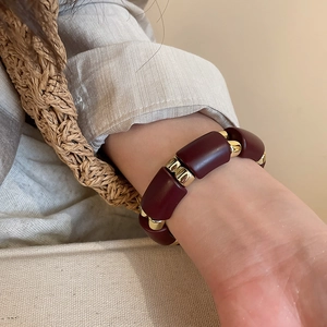 Detailed shot of vintage acrylic bead bracelet with burgundy tiles and gold accents