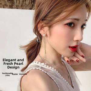Detail of long pearl tassel earrings featuring gold metal chains on an elegant female model