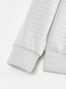 Gedetailleerd overzicht van witte gewatteerde sweatshirtstof met geribbelde elastische manchetten